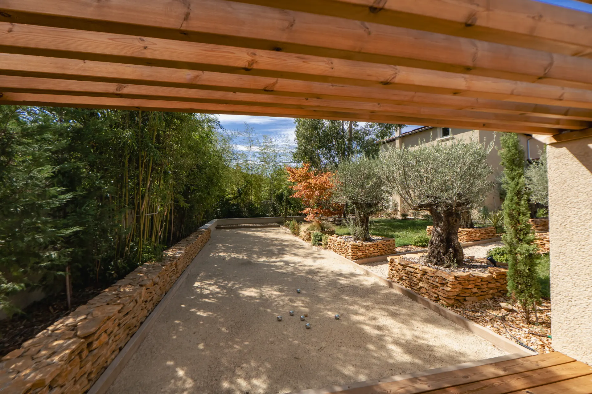 Terrain de pétanque sous pergola bois, oliviers et bambous