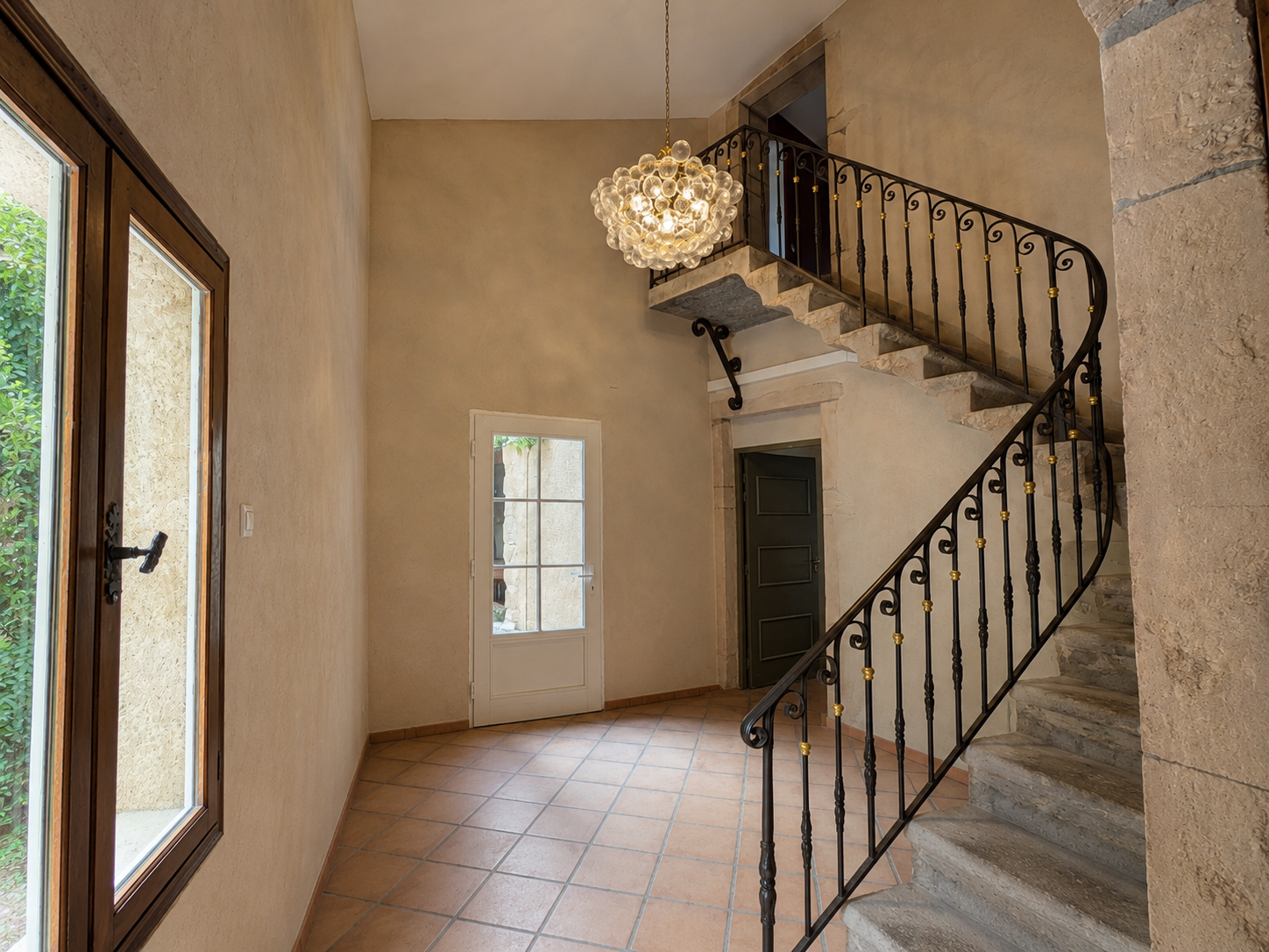 Hall d'entrée avec escalier en pierre et rampe en fer forgé